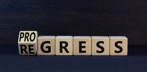 Regress or progress symbol. Turned wooden cubes and changed the word Regress to Progress. Beautiful black table black background. Business regress or progress concept. Copy space.