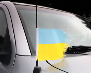 Close up of a Ukrainian flag attached to an automobile antennae blowing in the wind.