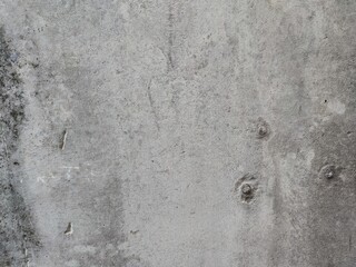 Rough cement surface. Light gray concrete surface with bulges and dents with cracks and pores. On the right side, there are three point inserts arranged in the form of a triangle.