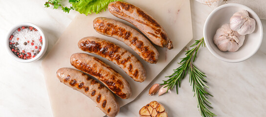 Delicious grilled sausages and spices on light background, top view