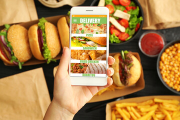 Woman with mobile phone ordering fast food online, closeup