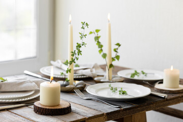 Rustic zero waste wedding decor with natural elements. Wooden table, candles, linen napkins, branches with green leaves. Eco-friendly decoration for the special dinner. Romantic and cozy place