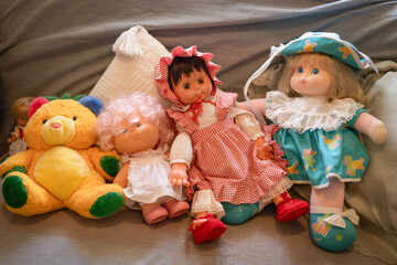 Some antique dolls and an orange teddy bear from a nostalgic collector