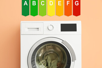 Modern washing machine with laundry and energy efficiency rating on color background. Concept of...