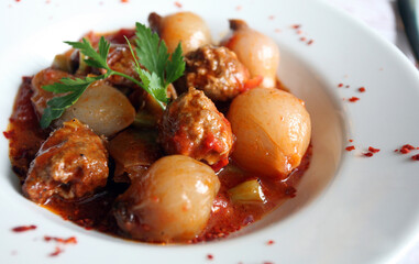 Slops meatballs and onions on the dinner plate.
