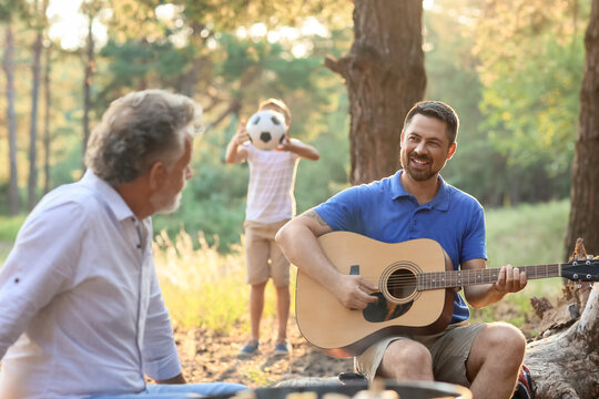 Handsome man playing guitar at barbecue party on summer day