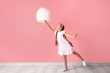 Cute little girl with cotton candy on pink background