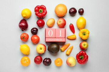 Different vegetables, fruits and cube calendar with date NOVEMBER 1 on grey background. World Vegan Day concept
