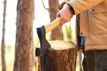 Male tourist chopping wood in forest, closeup