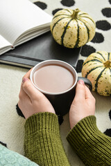 Woman drinking tasty pumpkin coffee on floor in room