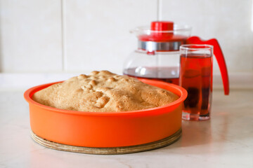 Making apple pie at home. Homemade pastry in silicone cake pan served with cherry fruit drink