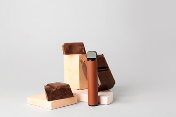 Disposable electronic cigarette and chocolate on light background