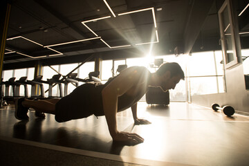 Young man doing push-ups as part of bodybuilding training in gym
