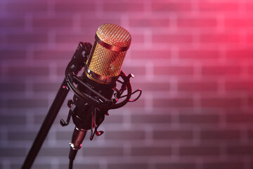 Closeup view of stand with professional microphone on dark brick wall background