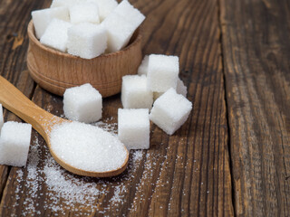 granulated sugar on a wooden spoon close-up on an old wooden table
