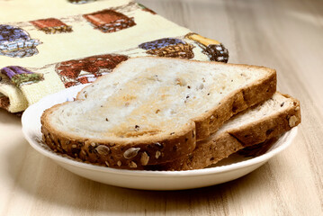 slices of toasted sliced bread with seeds on a plate on a table. warm colors