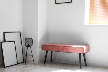 Pink bench with lamp and blank frames in light room