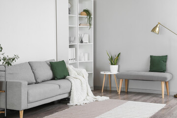 Interior of light living room with soft bench, sofa and shelving unit