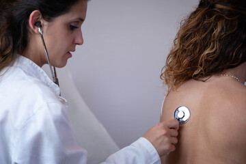 Doctor visits patient in her office. Doctor listens to the patient's chest with a stethoscope,...