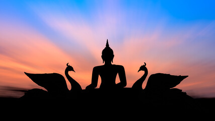 Silhouette with buddha on sunset background.