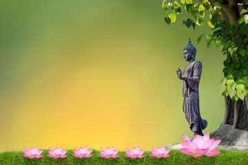 Buddha statue standing under bodhi tree on bokeh nature background.
