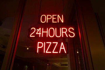 Neon sign in the window of a pizzeria. ¨Open 24Hours Pizza¨
