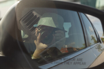 An unrecognizable person in a car using the rear view mirror to take a picture of himself
