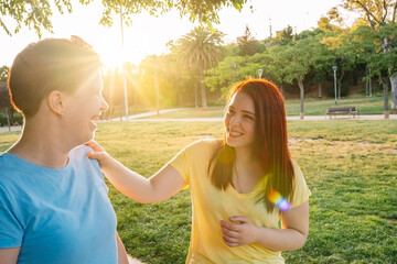 two great friends chatting and strolling happily, in a city public park at sunset. young girls...