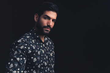 bearded Latin American handsome man looking severely into the camera copy space black background studio shot medium closeup. High quality photo