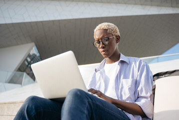 African American programmer using laptop computer working freelance project sitting at workplace....