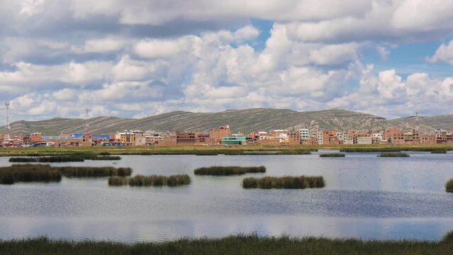 View Of The Lake With Reeds, Town And The Mountain Range In The Distance