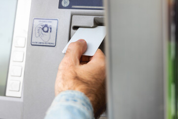 Male hand inserting ATM card into ATM bank machine