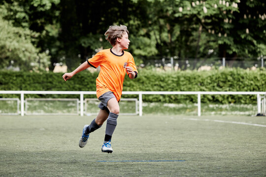 jeune garçon joue au foot en orange