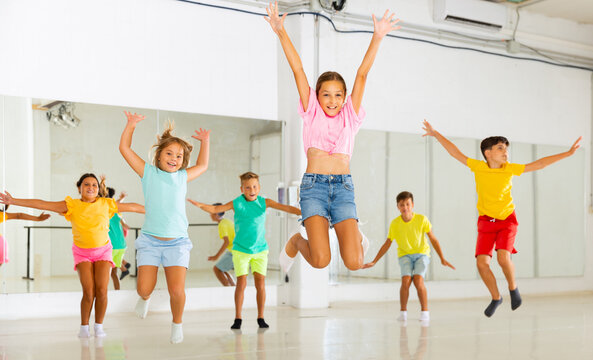 Group Of Cheerful Tweens Having Fun And Jumping During Modern Dances Class.