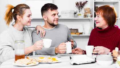 Portrait of happy family enjoying conversation over cup of coffee at home