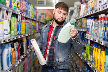 Focused guy looking for household detergents on shelves in shop
