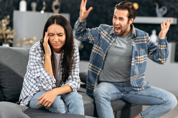 Family quarrel, disagreement, misunderstanding. Family caucasian couple sitting on a sofa in the...