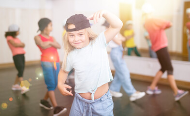 Cute tween girl hip hop dancer posing during workout in group dance class for children..