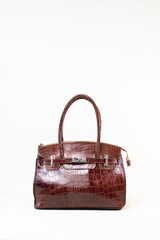 Brown female hand bag with two handles on white background isolated, crocodile texture