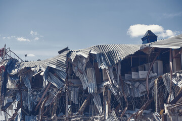Damaged shop center due to building demolition surrounded with rubble and scrap. Building...