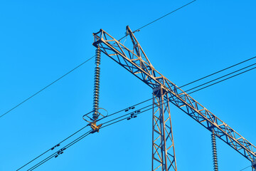 High voltage electricity tower with power line against blue sky. Overhead electric power line with...