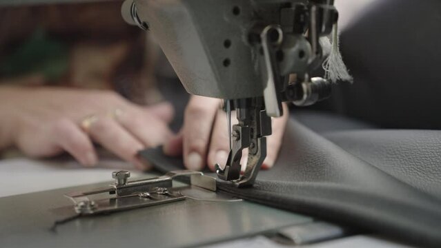 sewing master special sewing machine sews leather product. making product from fabric leather. tailor working. hands close-up. production industry concept. workshop seamstress couturier order clothes.