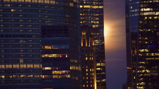 Full Moon backlit buildings, during nighttime in the city of New York - handheld shot from a ferry