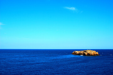 Fototapeta na wymiar Beautiful panorama in Polignano a Mare with the deep blue Adriatic sea and a massive rock on the right under the azure sky on a sunny summer day