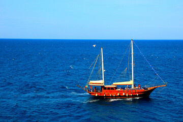 Fototapeta premium Romantic scene in Polignano a Mare with intense blue waters of the Adriatic sea and a majestic sailing ship under the azure sky on a fine sunny day
