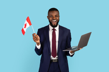 Excited Black Businessman With Canadian Flag And Laptop Posing Over Blue Background