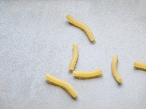 Closeup of Italian food yellow raw uncooked vermicelli, macaroni, noodle, pastry, pasta on isolated gray cement (close-up, meal, cuisine, cooking, gray, dry, dish, studio, plate, dinner, tile, cement)