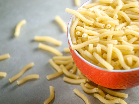 Artisanal Pasta in a Red Bowl - Closeup of Italian food yellow raw uncooked vermicelli, macaroni, noodle, pastry, pasta on the isolated red bowl