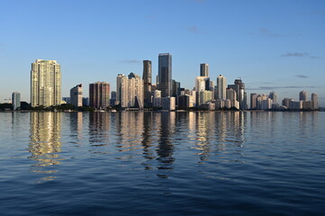 Naklejka premium Skyline of City of Miami, Florida reflected in calm water of Biscayne Bay on clear sunny morning.