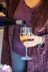 A woman in the winter pouring a glass of white wine